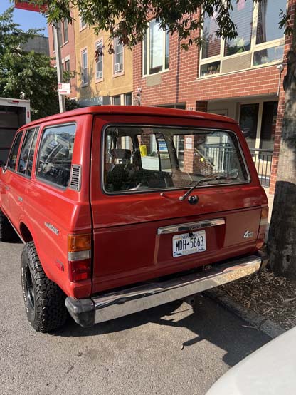 Red vintage Jeep Cherokee parked on city street
