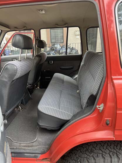 Red vehicle rear interior with striped bench seat
