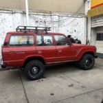 Red vintage SUV with roof rack parked outside garage