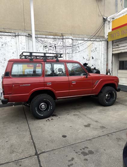 Red vintage SUV with roof rack parked outside garage