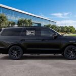 Black luxury SUV parked beside modern glass office building