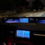 Car dashboard displays navigation while driving on a dark road.