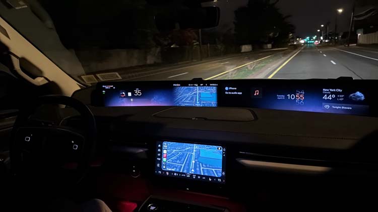Car dashboard displays navigation while driving on a dark road.