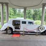 Vintage white limousine displayed under a columned entrance