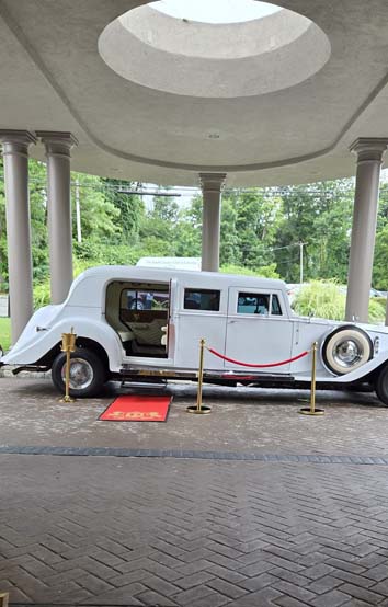 Vintage white limousine displayed under a columned entrance