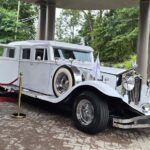 White vintage limousine parked beneath a covered entrance