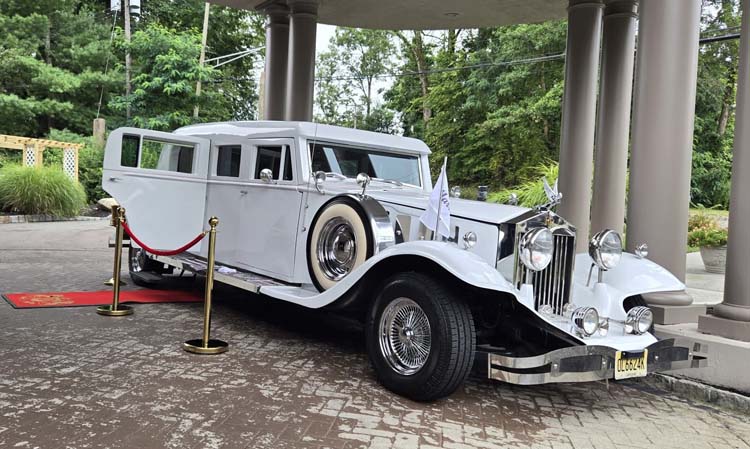 White vintage limousine parked beneath a covered entrance