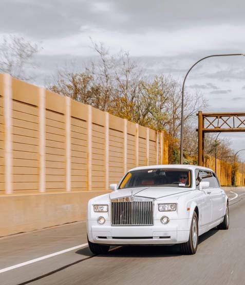 White luxury sedan driving on a city road