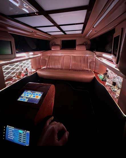 Luxury limousine interior with leather seating, bar, and touchscreen controls